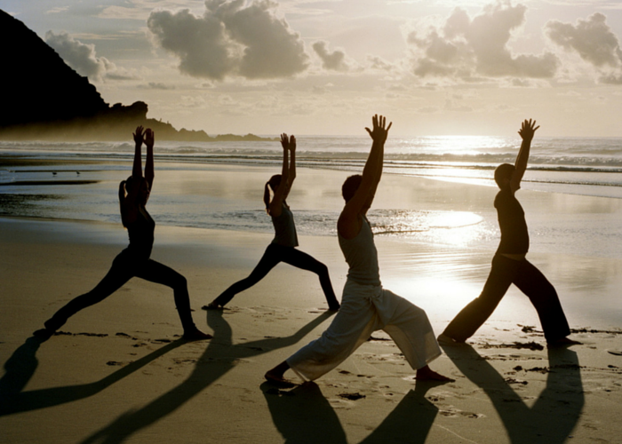 Persone che fanno yoga in spiaggia